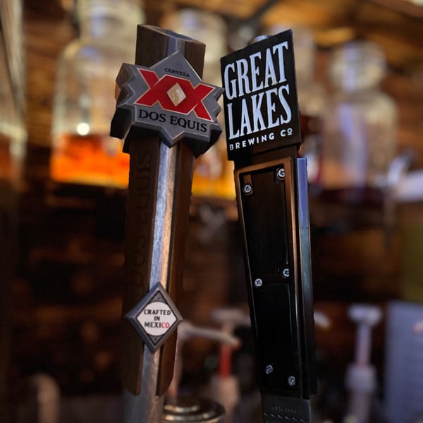 Close-up of two beer tap handles, one for Dos Equis and one for Great Lakes Brewing Co.
