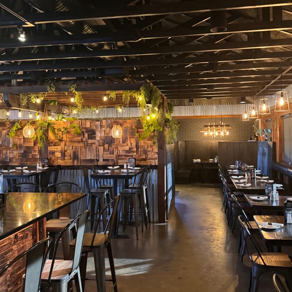 Interior of Casa Nueva Mexican Restaurant with rustic wood walls, industrial lighting, and set tables.